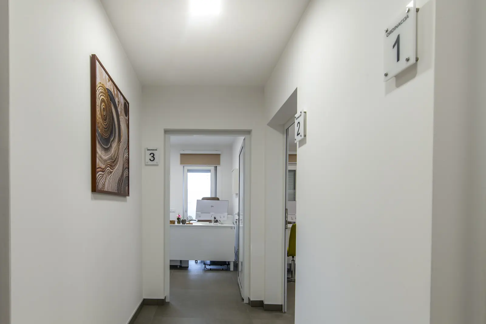 Corredor iluminado de um escritório com salas numeradas